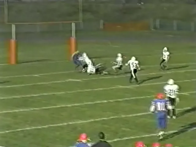 A videotape frame from 2003: a tackle near the goalposts, seen from the sideline.
